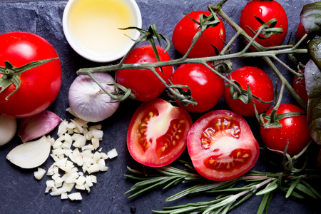 sauce ingredients close up photo: tomatoes, garlic, oil, roosemary on slate tray with oil,basil, rosemaryの写真素材