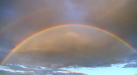 Full double rainbow in the sky against the background of cloudsの写真素材