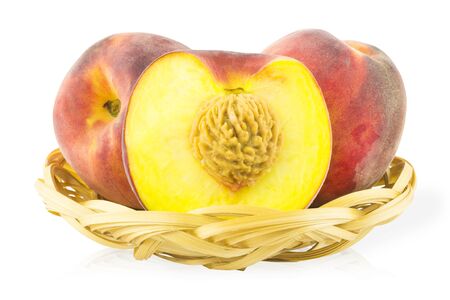 Two peaches and peach with a cut in the basketの写真素材
