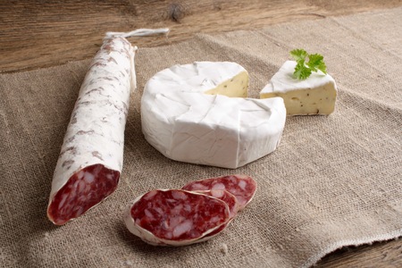 Traditional sliced salami on wooden board with brieの写真素材