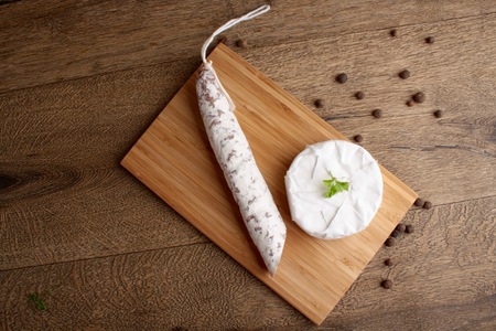 Traditional sliced salami on wooden board with brie