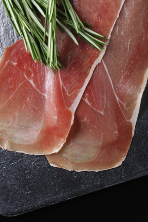 prosciutto jamon ham on a stone background rosemaryの写真素材
