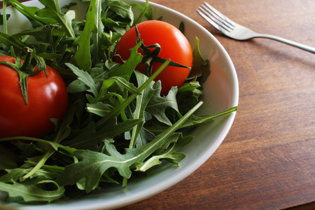 salad of rucola tomato on a wooden backgroundの写真素材