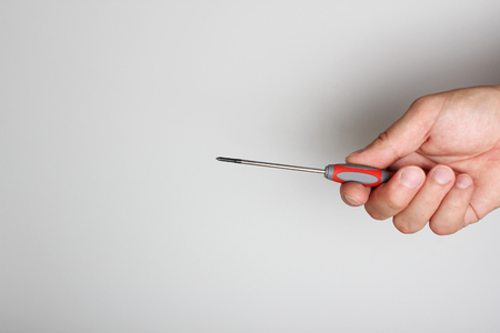 screwdriver repair in hand on a light backgroundの写真素材
