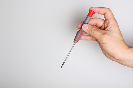 screwdriver repair in hand on a light backgroundの写真素材