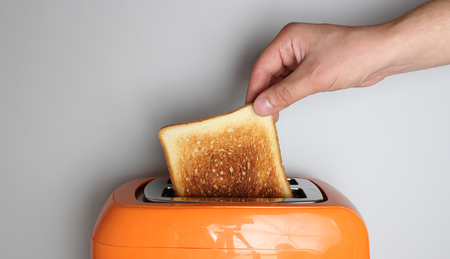hand toast and orange toaster on a light background