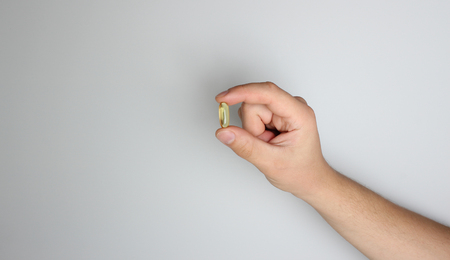 yellow capsule in hand on a light backgroundの写真素材