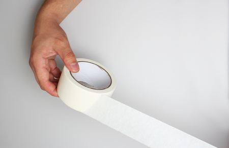hand and  paper tape on a gray backgroundの写真素材