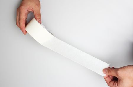 hand and paper tape on a gray backgroundの写真素材