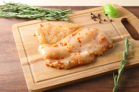 chicken breast in marinade spice, board, rosemaryの写真素材