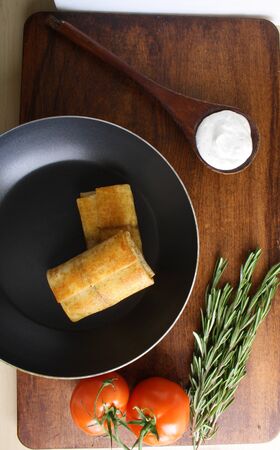 pancakes with meat in a frying pan and sour creamの写真素材