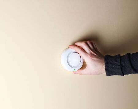 fire alarm sensor hand on an orange light backgroundの写真素材