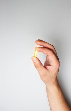 yellow capsule in hand on a light backgroundの写真素材