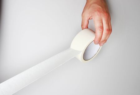 hand and Scotch tape on a gray backgroundの写真素材