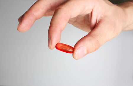 red capsule COVID-19 medicine in hand lettering COrona VIrus Diseaseの写真素材