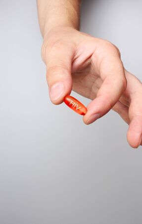 red capsule hiv medicine in hand letteringの写真素材