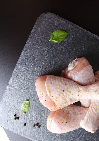 fresh chicken drumstick on a dark stone backgroundの写真素材