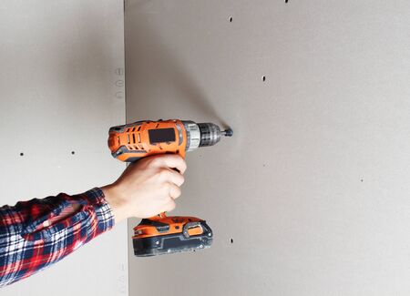 mounting drywall screwdriver hand in gloveの写真素材