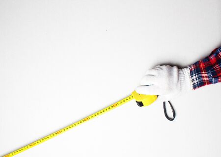yellow tape measure in hand construction gloveの写真素材