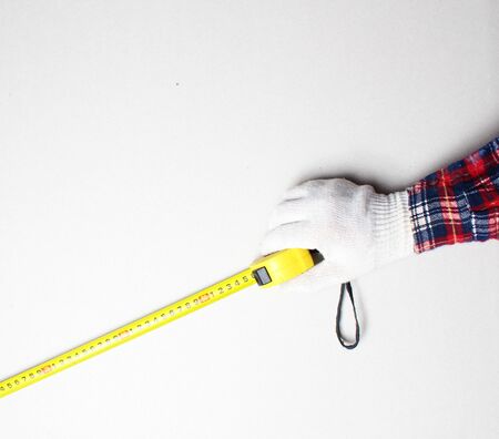 yellow tape measure in hand construction gloveの写真素材