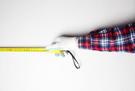yellow tape measure in hand construction gloveの写真素材