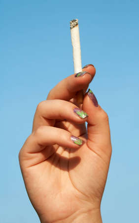 woman hand with cigarette with blue sky on the backgroundの写真素材