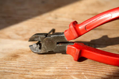 Nippers with the clamped nail on a wooden tableの写真素材
