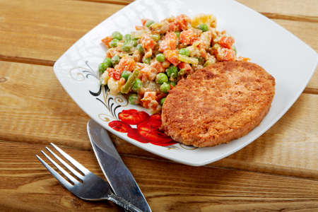 Fish cutlet with a vegetable garnish on a tableの写真素材