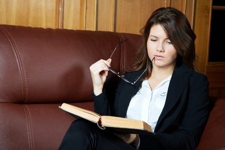 The girl in a suit reads the bookの写真素材