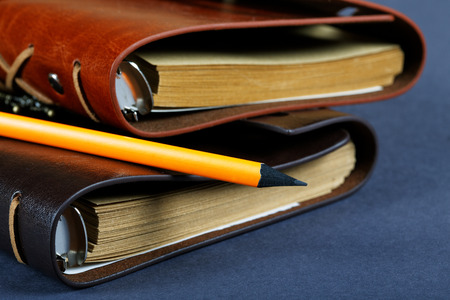 Pile of notebooks in leather covers and a pencil close up