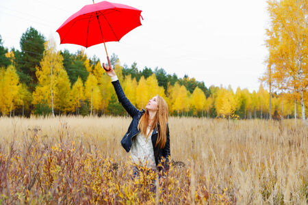 The girl with a red umbrella in autumn parkの写真素材