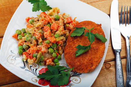 Fish cutlet with a vegetable garnish on a tableの写真素材