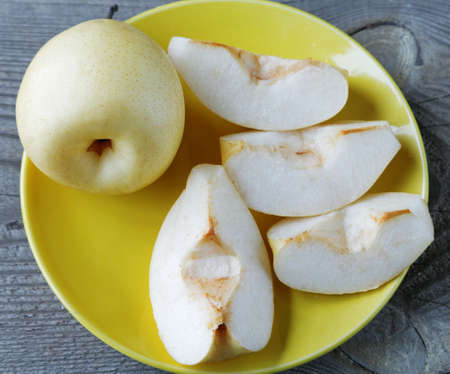 sliced yellow pear in a bowl on a rustic tableの写真素材