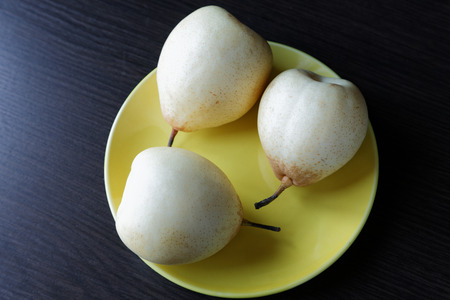 Three yellow pears on the plate on the tableの写真素材