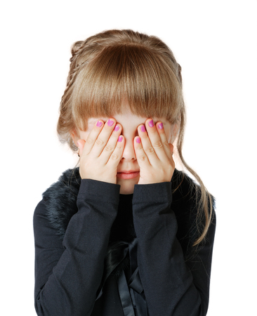 Little girl covers her face with hands on a white backgroundの写真素材