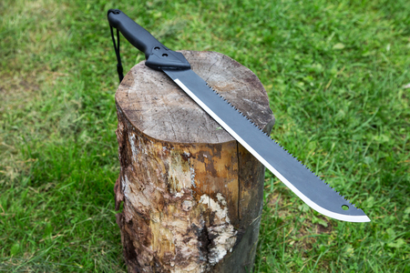 machete on a stump close up on a grass background