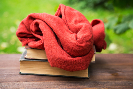 female scarf and books on the table on the grass backgroundの写真素材