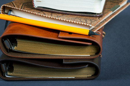 Pile of notebooks in leather covers and a pencil close upの写真素材
