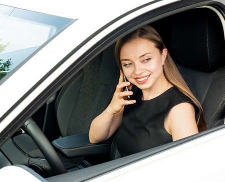 Modern beautiful woman businesswoman with glasses peeks out of her car.の写真素材