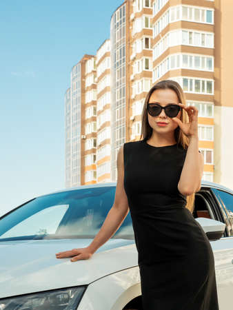 Modern beautiful woman businesswoman stands near her car.の写真素材