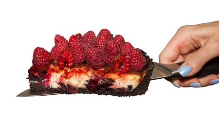 Woman's hand holds the raspberry cheesecake with the knife. The still life is isolated on a white background.の写真素材