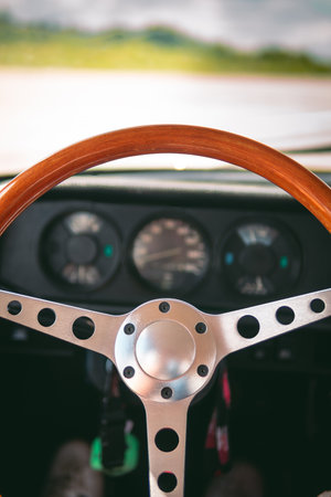 Looking through the window of a rusty blue vintage car at the nostalgic steering wheel. Shades of blue, slight reflections in the window pane and a blur in the foreground.の写真素材