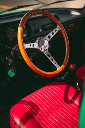 Interior of an old car with a vintage steering wheel, red leather and wooden parts, retro car...