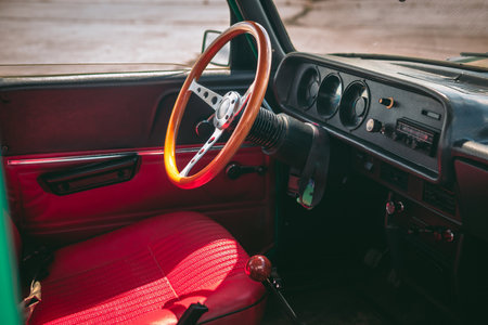 Interior of an old car with a vintage steering wheel, red leather and wooden parts, retro car...