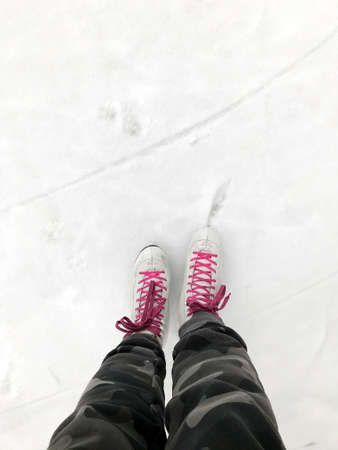 Girl in dress skates mittens tying shoelaces and prepare for skatingの写真素材
