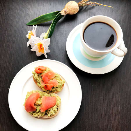 coffee and sandwiches with salmon and avocado on a plate