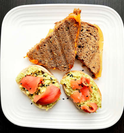 Healthy sandwich with avocado and salmon. Wooden background. Top view
