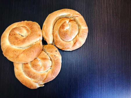 Traditional Greek pastries. Snail with meat or cheese. Roll with filling on a wooden rustic.の写真素材