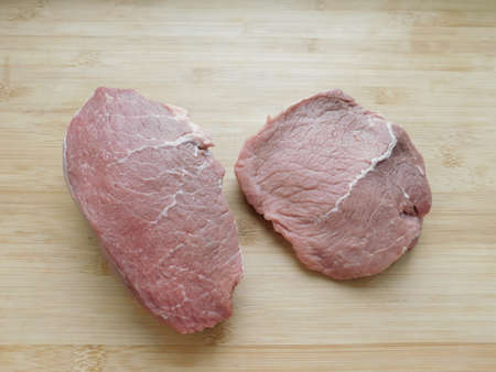two slices of fresh beef on a wooden table