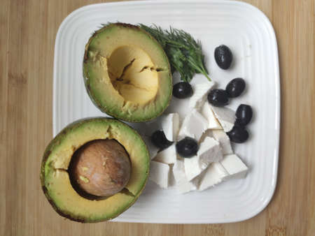 breakfast with avocado, cheese and olives on a plate